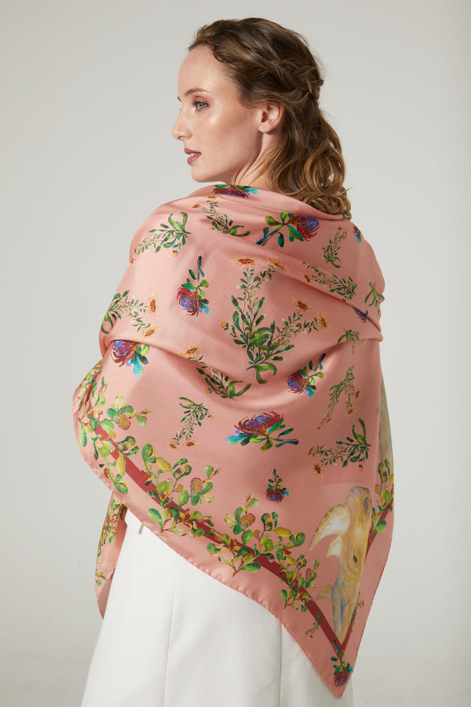 Mujer de espaldas con echarpe grande de seda natural rosa con flores, hojas y rinocerontes