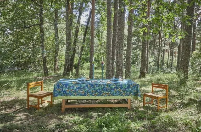 Mantel de lino y algodón orgánico color azul, sobre mesa larga en el bosque