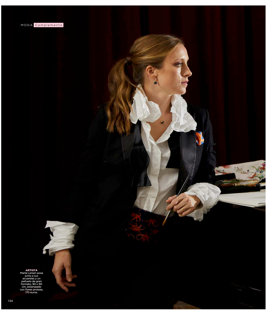 Artista Marta Larsen con pincel en mano y acuarela con fajín de seda natural pura y camisa blanca con volantes en cuello y mangas, revista Fuera de Serie