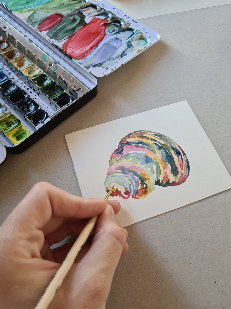 Detalle pintando caracola con pincel y acuarela