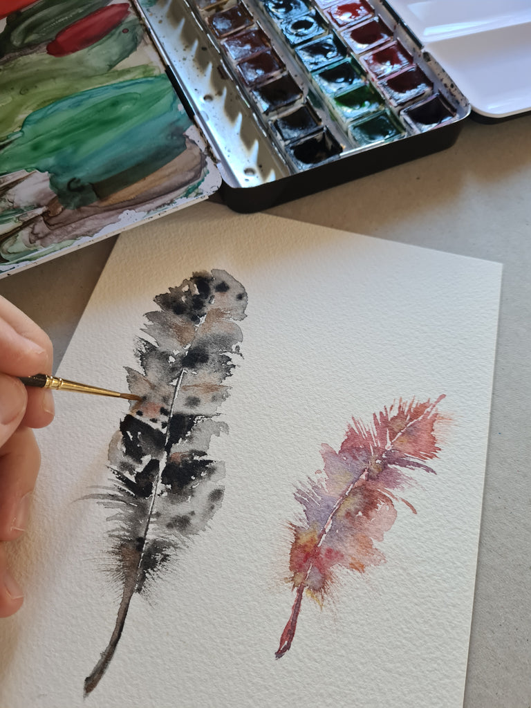 Detalle plumas negra y rosa pintadas a mano con acuarela