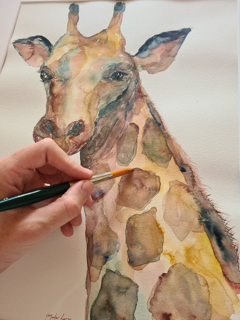 Detalle de mano con pincel pintando jirafa con acuarela