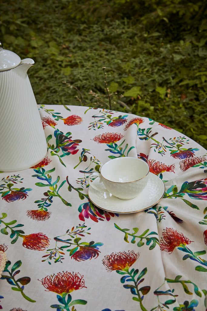 Detalle mesa de té con mantel de algodón y lino blanco con flores proteas