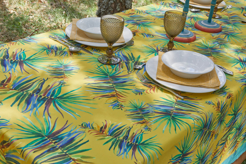 Detalle mesa puesta para dos personas con mantel de lino y algodón amarillo con flores verdes