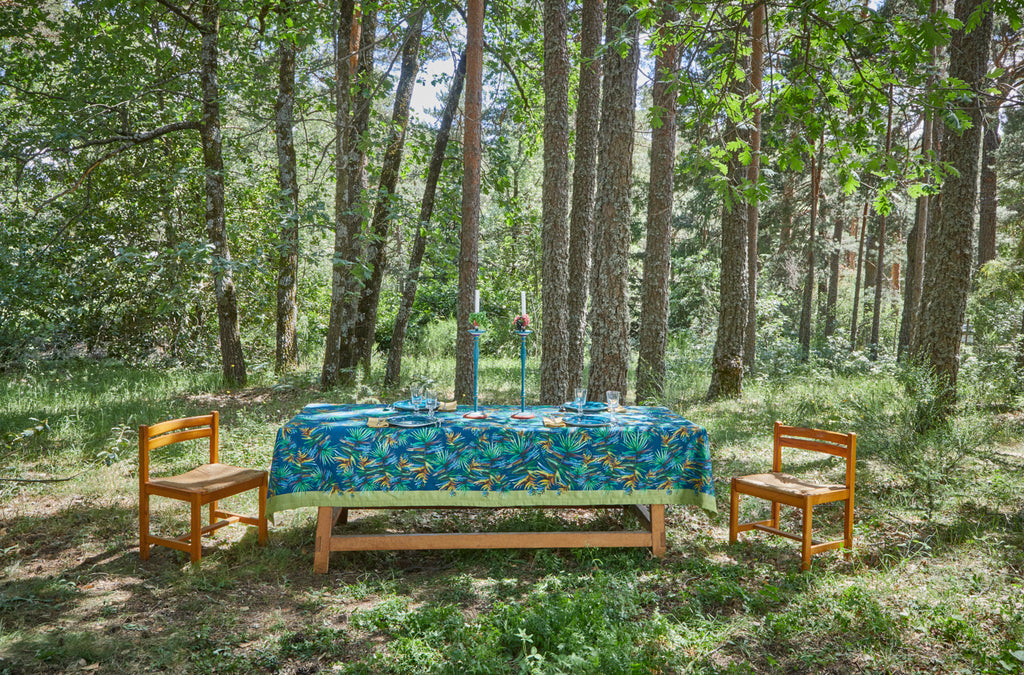 Mesa alargada en el bosque con mantel de lino y algodón azul marino con diseños de hojas verdes