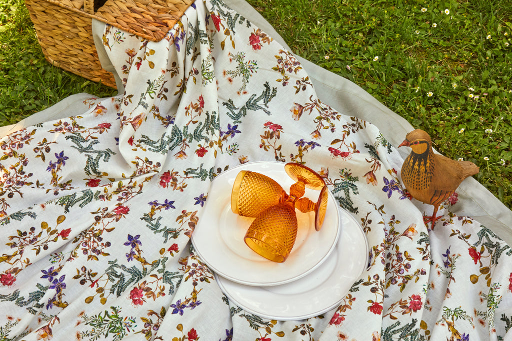 Detalle de picnic con mantel de lino y algodón blanco con flores