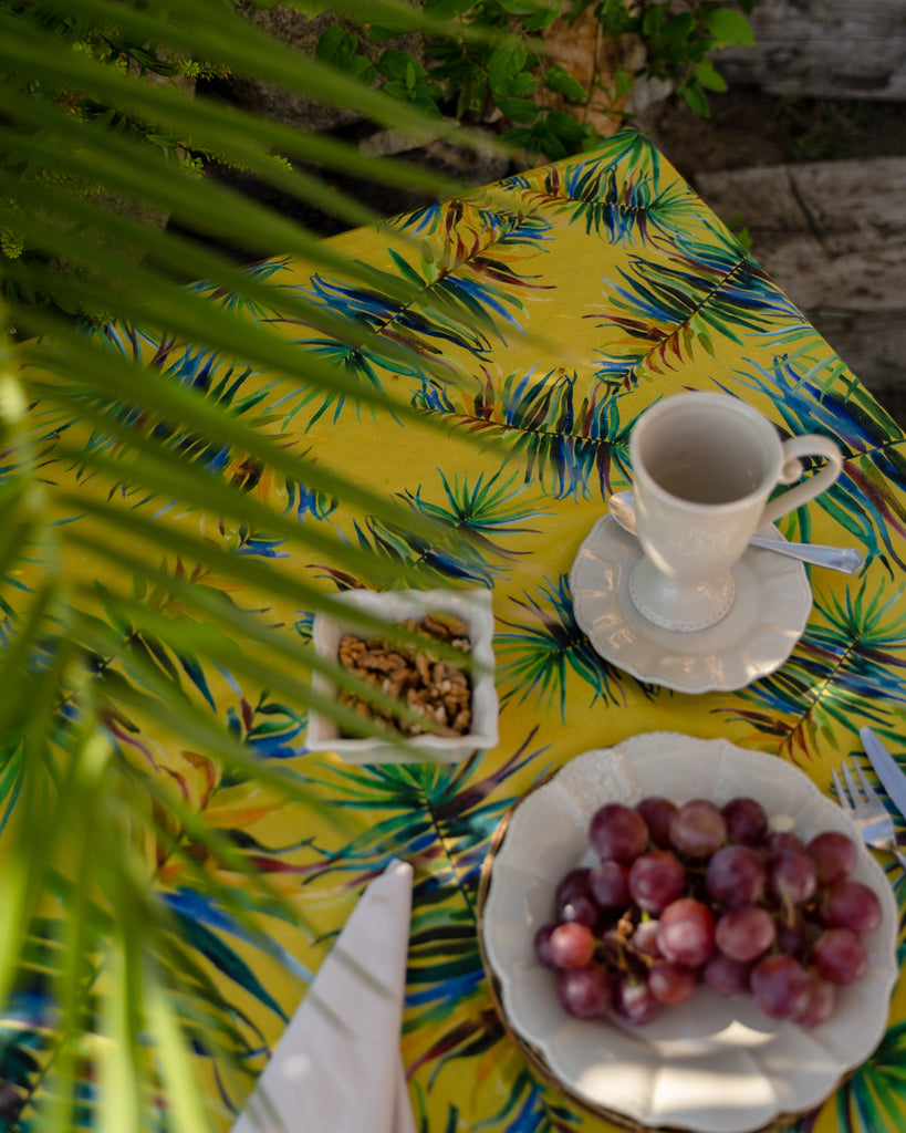 Detalle mesa pequeña cuadrada con mantel de lino y algodón amarillo con hojas verdes