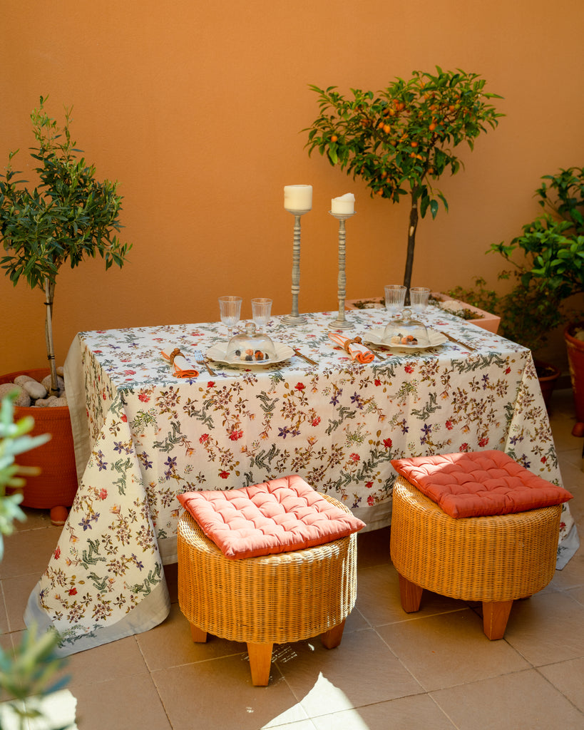 Mesa puesta en terraza para dos personas con mantel de lino y algodón blanco con flores