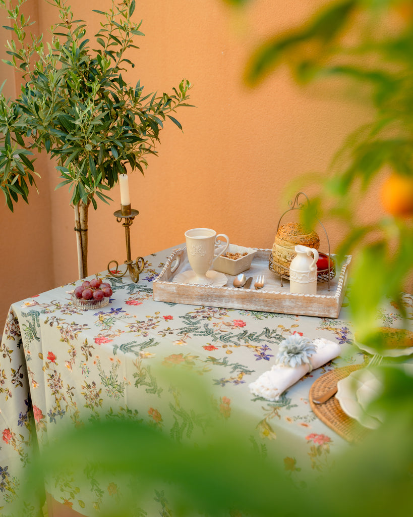 Detalle mesa en terraza con mantel de lino y algodón gris con flores