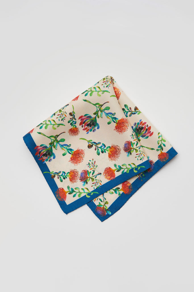 Detalle pañuelo de seda natural con flores proteas fondo beige y marco azul
