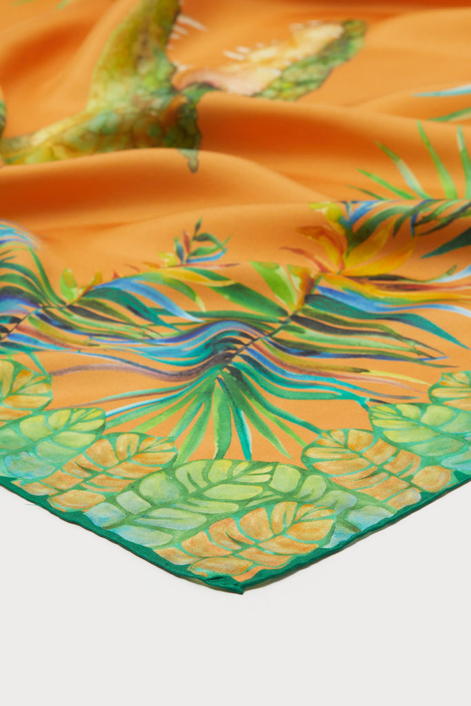 Detalle foulard de seda natural pura con verdes y naranjas y diseños de hojas y cocodrilos