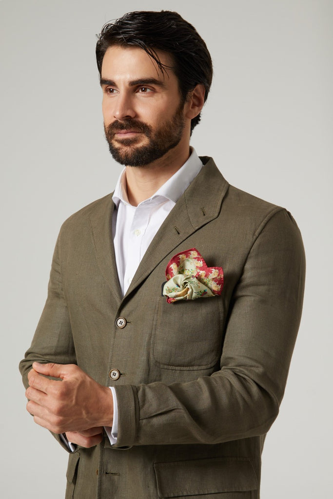 Hombre con chaqueta verde y pañuelo de seda natural cuadrado en el bolsillo superior