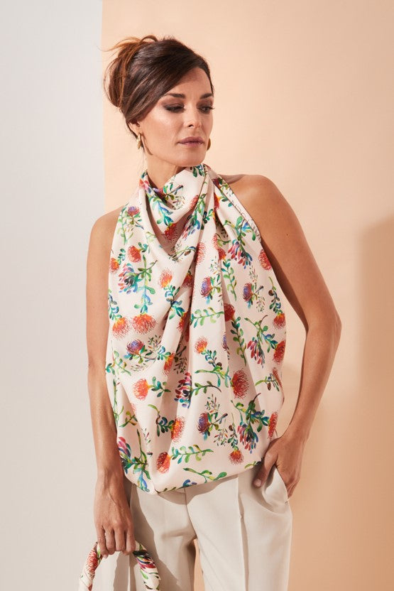 Mujer elegante con top de seda natural crudo atado al cuello con flores proteas