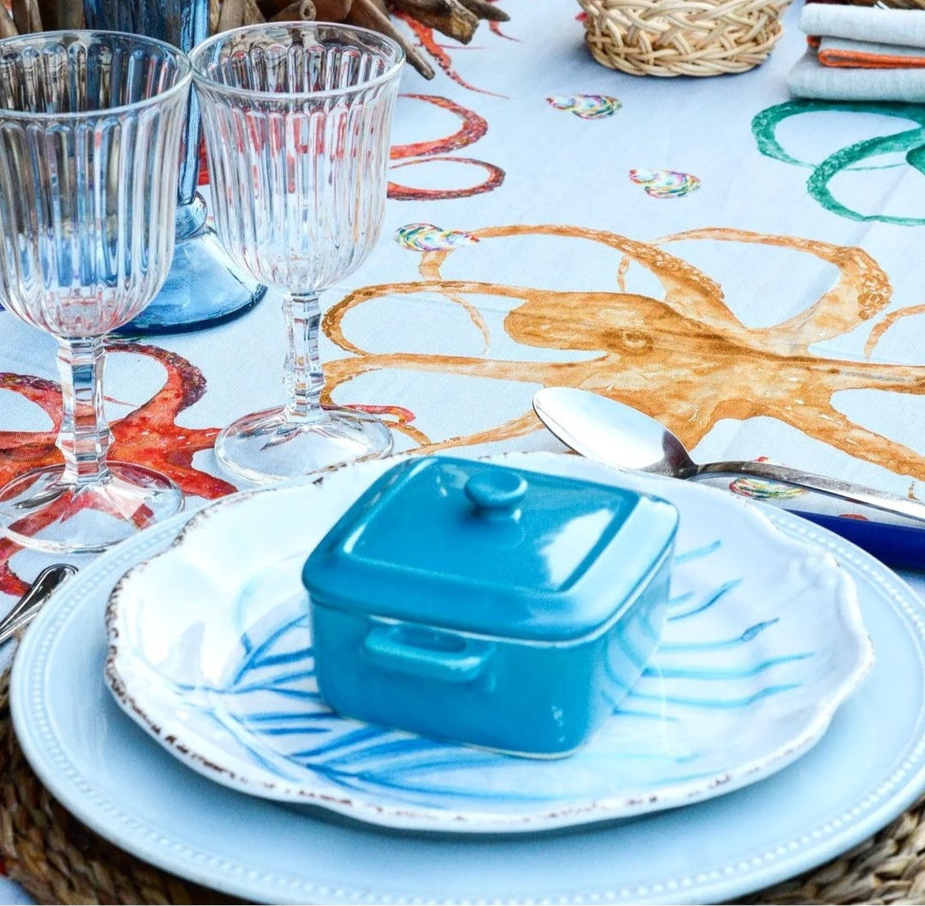 Detalle de mesa puesta con mantel de lino y algodón blanco con pulpos y caracolas de colores