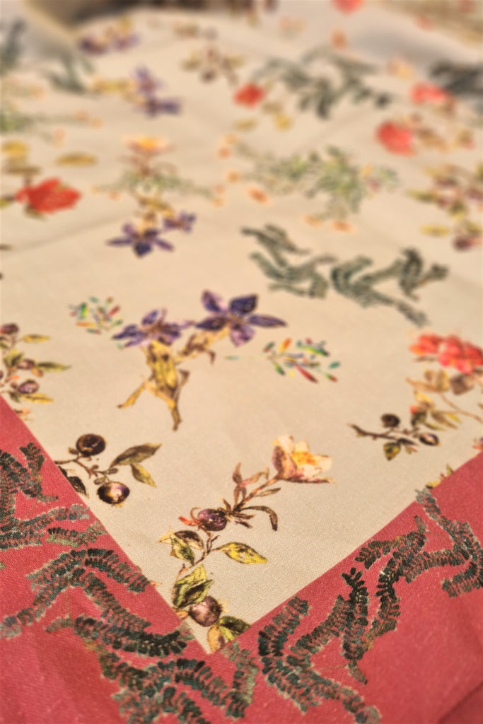 Detalle de mantel de lino y algodón gris con flores y marco naraja