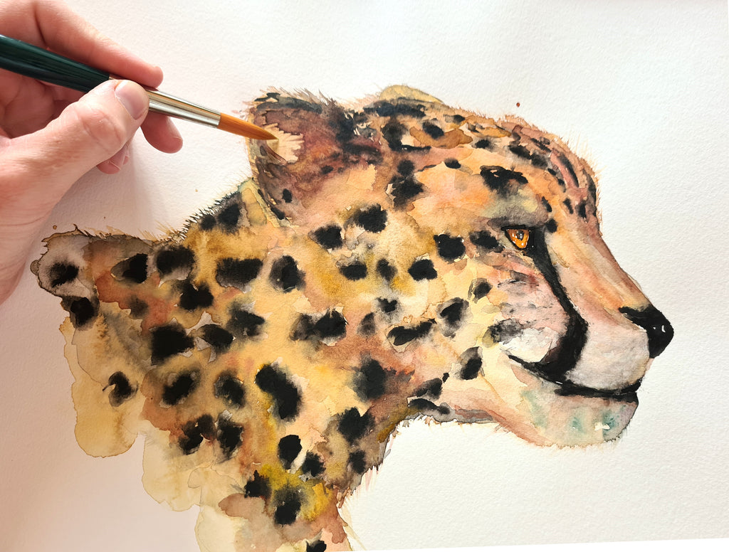 Mano con pincel pintando guepardo con acuarela