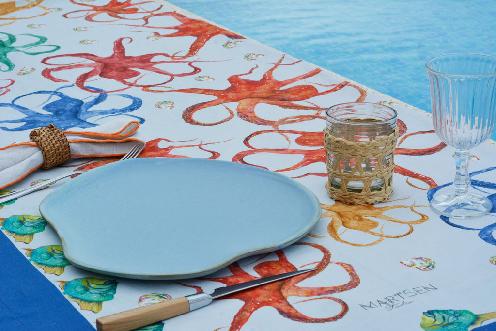Detalle de mesa con mantel  blanco de lino y algodón con diseños de pulpos y animales marinos
